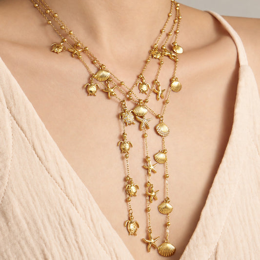 Gold ocean charm Y lariat necklaces layered on model with marine-inspired pendants