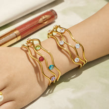 Wrist detail of a gold three-layer open bangle with cubic zirconia