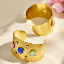 Front and back views of a gold open cuff bracelet with multicolor cat-eye effect stones