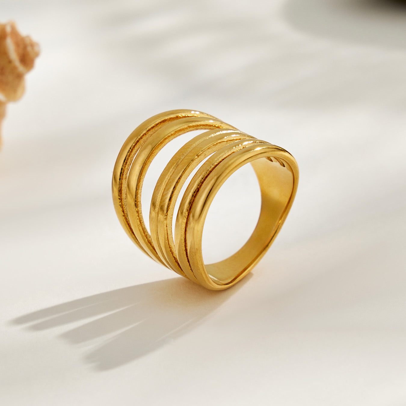 Gold tone 316L stainless steel irregular open statement ring in a clean product display