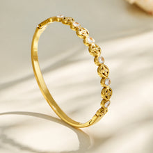 Side view of a gold openwork flower hinged bangle bracelet