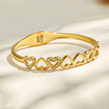 Gold openwork heart bangle with clear cubic zirconia accents on a light background