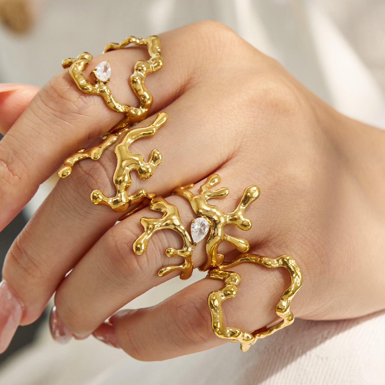 Close-up of gold 316L stainless steel organic open rings styled across multiple fingers