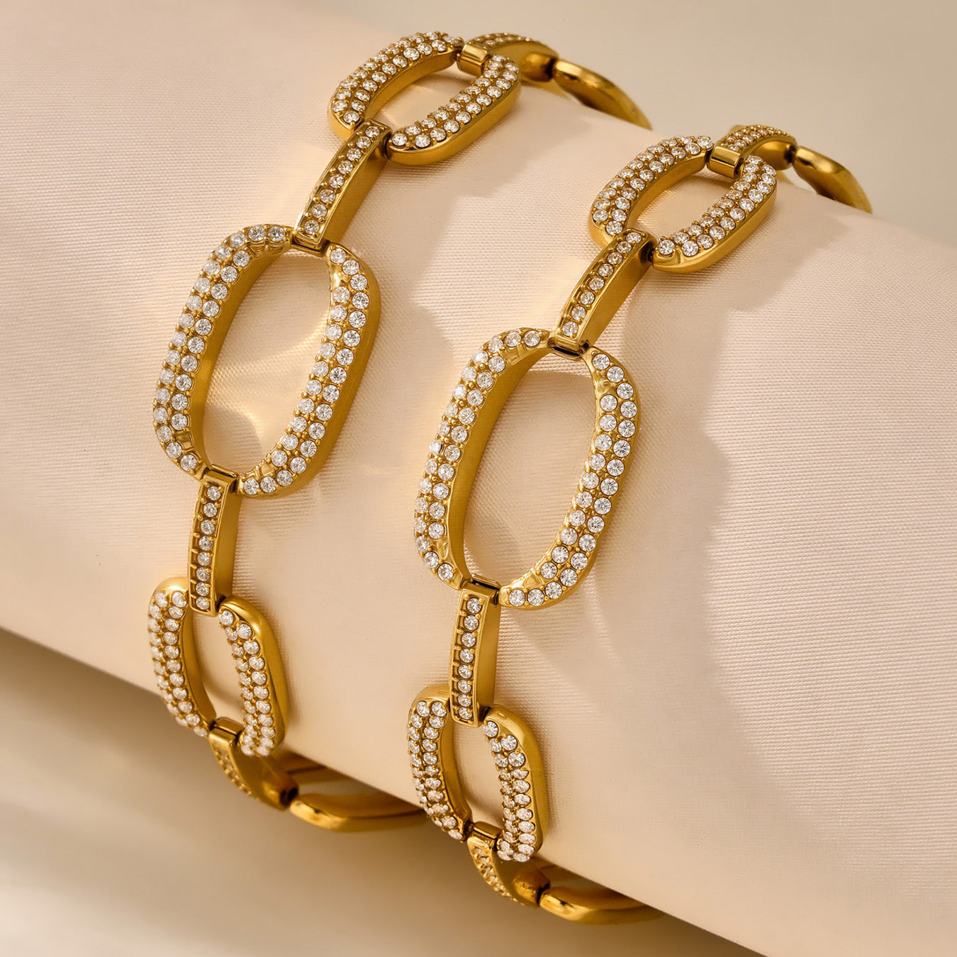 Pair of gold oval link bracelets with clear zircon borders