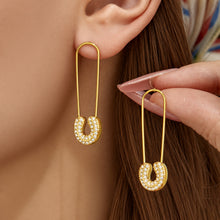 Close-up of a model wearing gold paperclip drop earrings