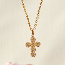 Close-up of a gold pavé zircon cross pendant on a fine chain