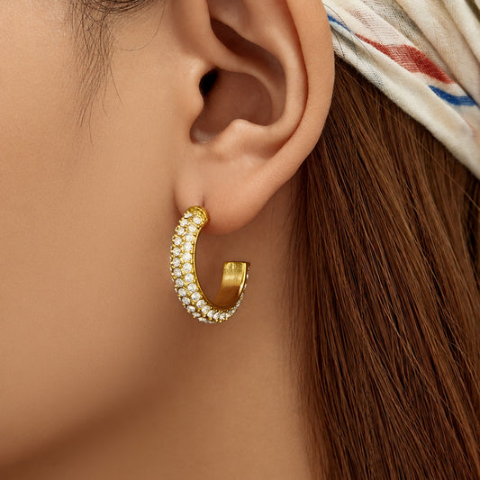 Model wearing gold C-shaped pavé cubic zirconia hoop earrings
