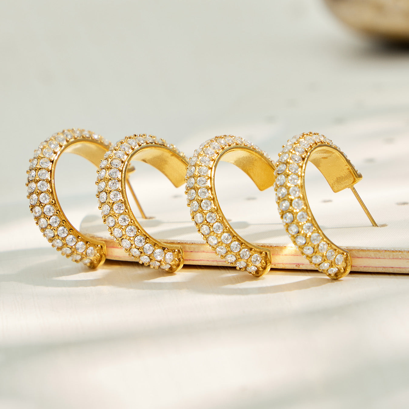 Multiple gold pavé cubic zirconia hoop earrings displayed together