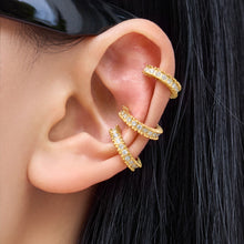 Model wearing multiple gold pavé zirconia ear cuffs along the upper and middle ear for a layered look