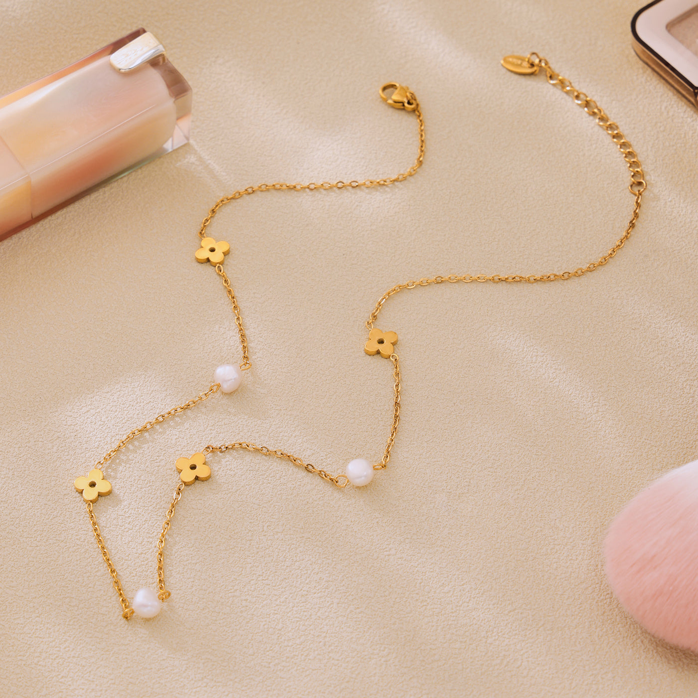 Close-up of a gold clover necklace with freshwater pearl accents and delicate stainless steel chain