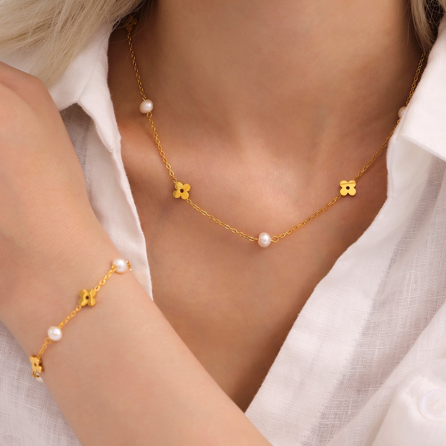 Model wearing a gold pearl clover necklace with small freshwater pearl accents around the neckline