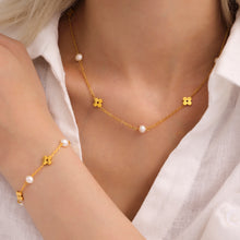 Model wearing a gold pearl clover necklace with small freshwater pearl accents around the neckline