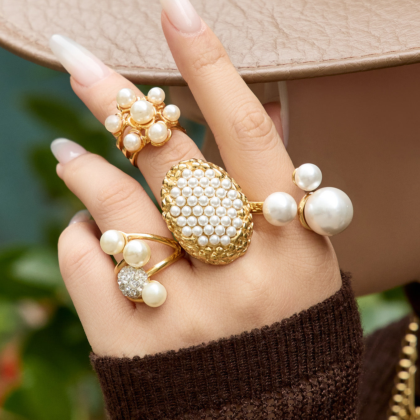 Model styling gold pearl cluster and open pearl rings with a neutral outfit