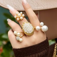 Model styling gold pearl cluster and open pearl rings with a neutral outfit