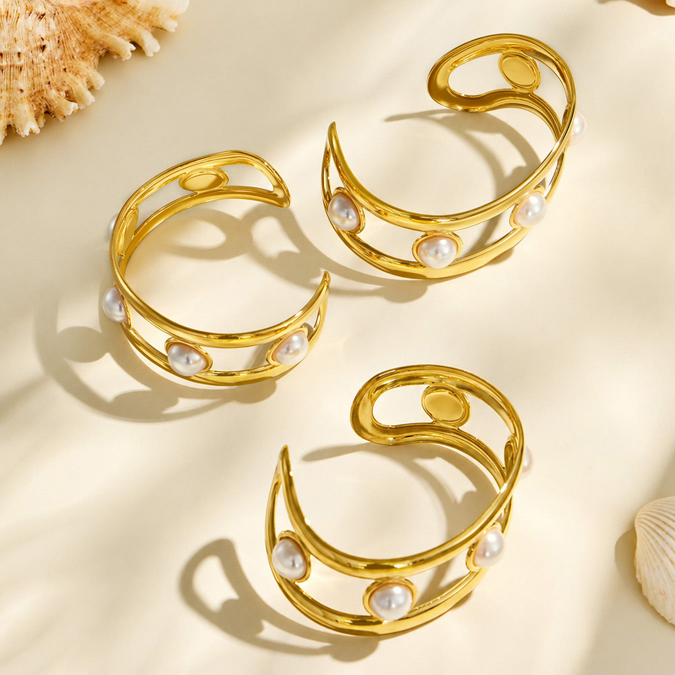 Two gold faux pearl cuff bracelets arranged together in a neutral flat lay