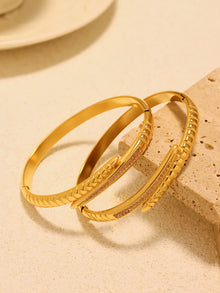 Pair of gold-tone nail bangle bracelets with ribbed detailing and pink zircon accents