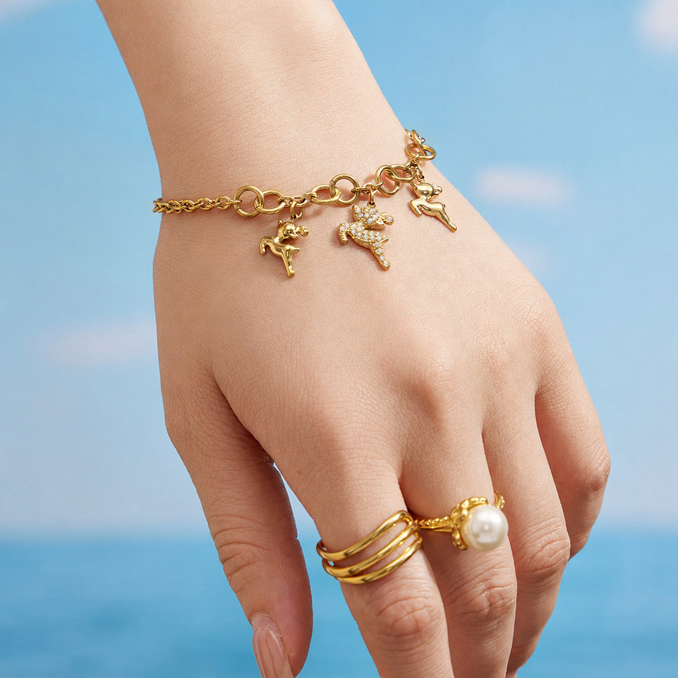 Gold reindeer charm bracelet worn on a model wrist in an outdoor setting
