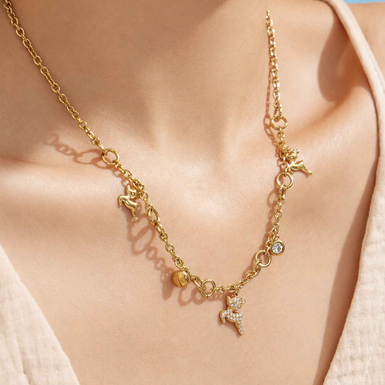 Close-up of a gold reindeer charm necklace with clear zircon accents at the neckline