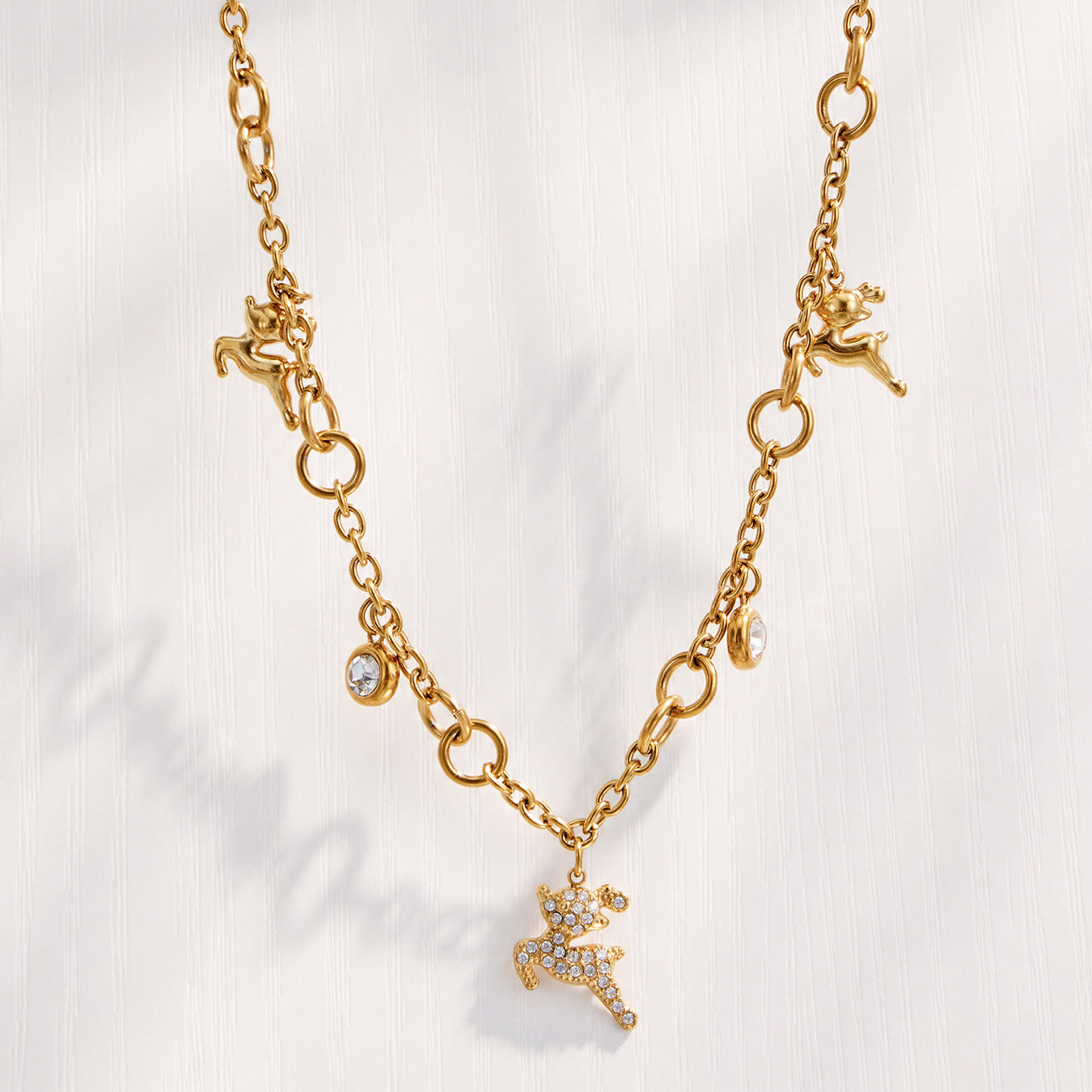 Model wearing a gold reindeer pendant necklace with clear zircon accents