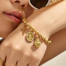 Lifestyle close-up of a gold religious charm bracelet with symbolic pendant details