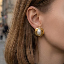 Model wearing chunky gold resin dome stud earrings with a rounded statement design
