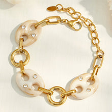 Close-up of a gold bracelet with cream resin mariner links and adjustable chain