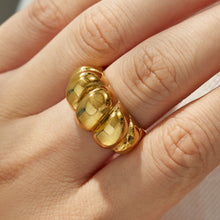 Close-up of gold tone sculptural 316L stainless steel rings worn on the fingers