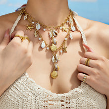Gold seashell charm necklace with starfish and faux pearl accents worn on model