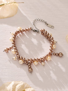Gold-tone shell pearl tassel bracelet displayed in a circular flat lay