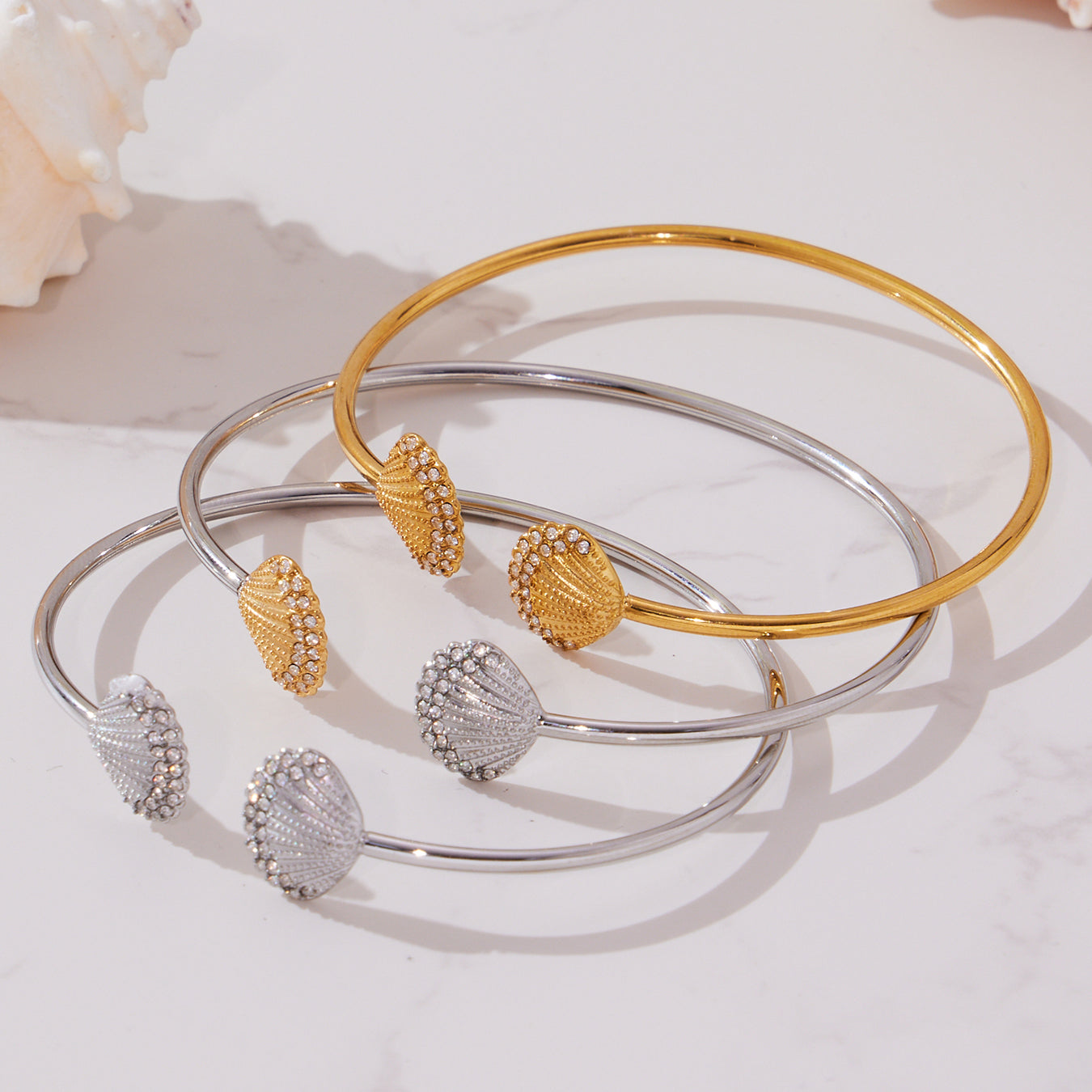 gold silver shell diamond cuff bracelets displayed on marble, stacked versatile style