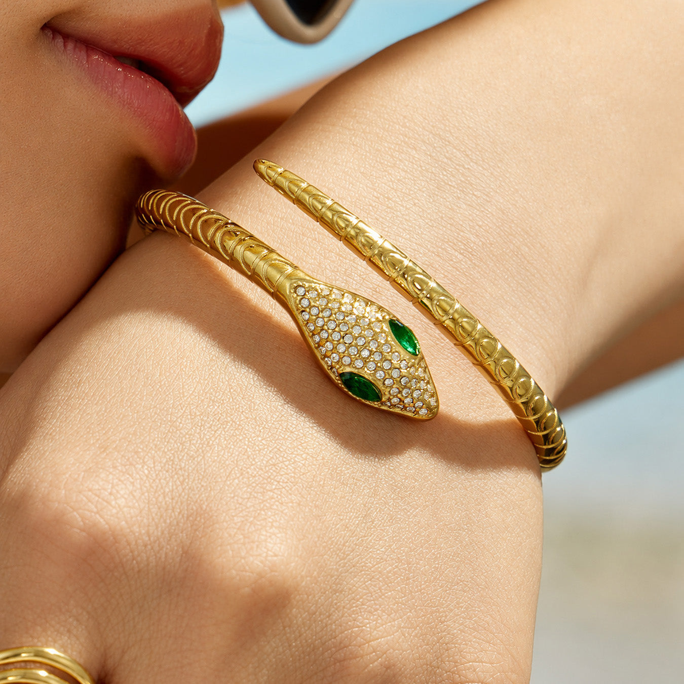 Close-up of the gold snake open bangle showing green zircon eyes and a pavé snake head