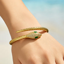 Model wearing a gold snake open bangle with green zircon eyes on the wrist