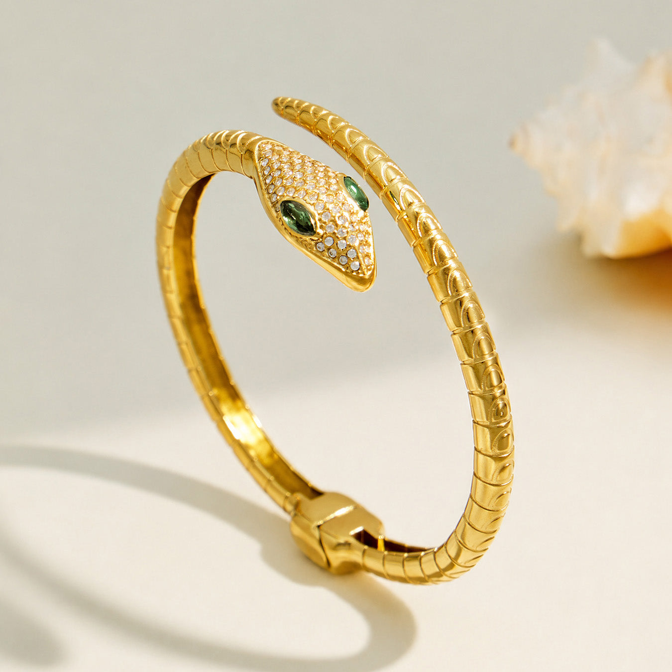 Side view of a gold snake open bangle with green zircon eyes and pavé details