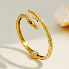 Side view of a gold snake open bangle with green zircon eyes and pavé details