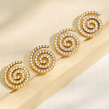 Gold spiral stud earrings displayed on a neutral fabric background
