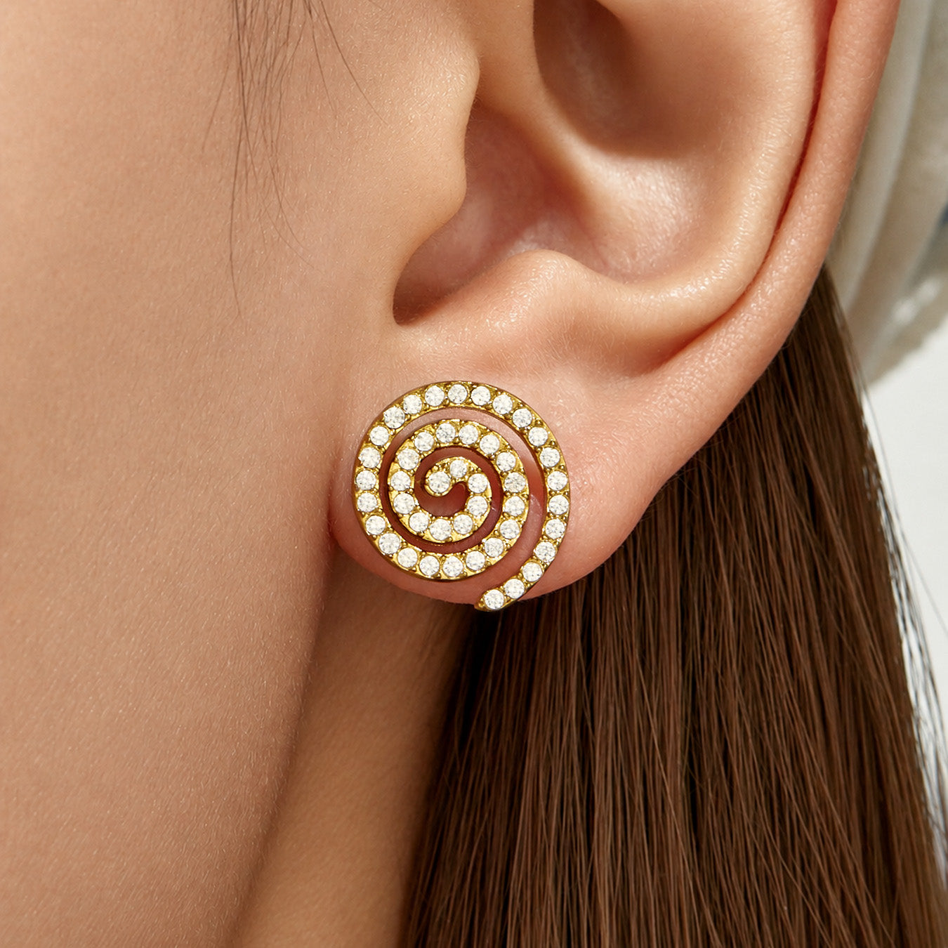 Side view of gold spiral stud earrings with clear cubic zirconia