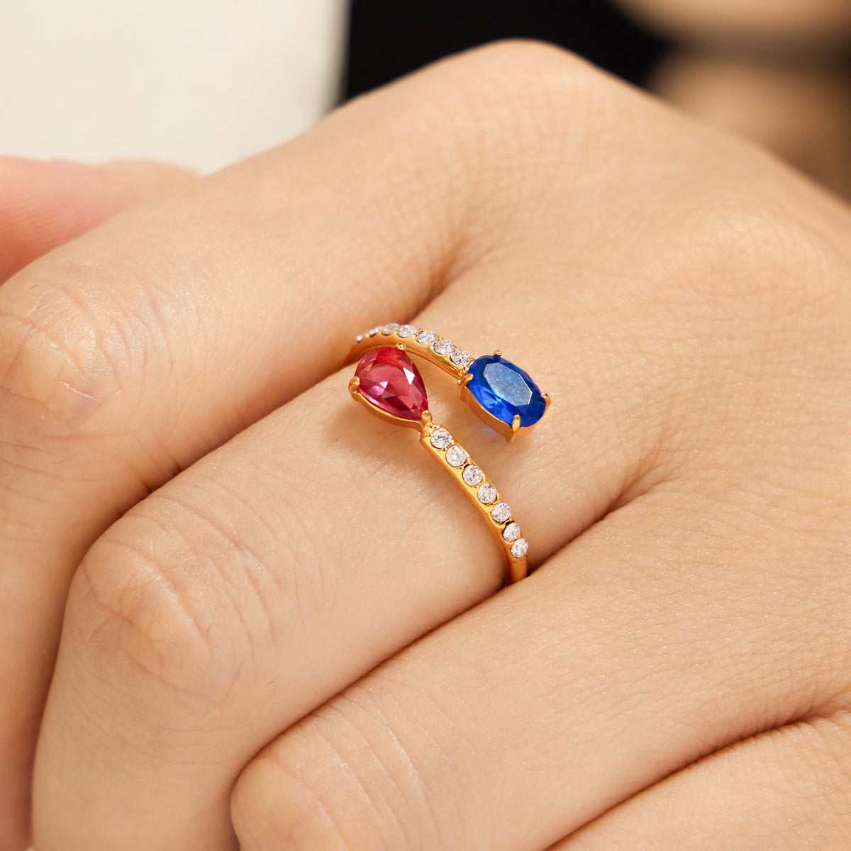 Gold-tone stainless steel open ring with white CZ and blue and pink colored glass on hand