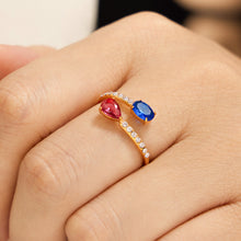 Gold-tone stainless steel open ring with white CZ and blue and pink colored glass on hand