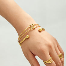 Gold-tone stainless steel knot cuff bracelet shown in close-up view