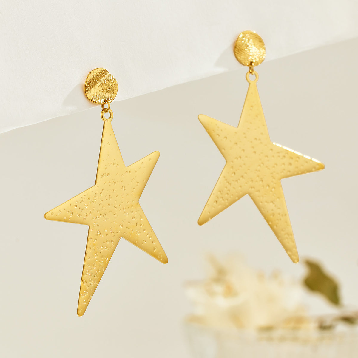 Pair of gold-tone stainless steel star drop earrings with textured geometric design