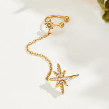 Single gold-tone stainless steel star chain ear cuff on a light surface, showing the curved cuff and stone-set starburst