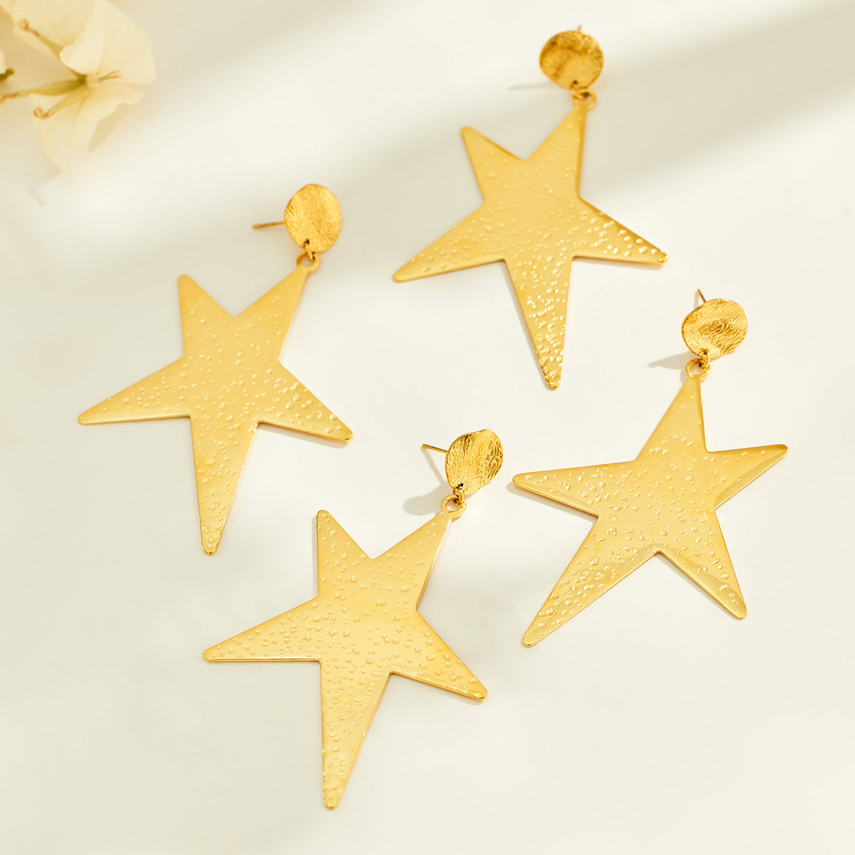 Gold-tone stainless steel star drop earrings displayed for wholesale selection
