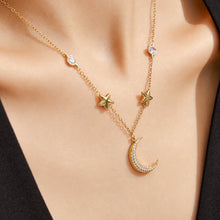 Model wearing a delicate gold star and crescent moon necklace with a white top