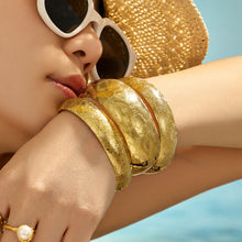 Close-up of a gold floral statement bangle worn on the wrist