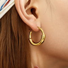 Gold chunky statement hoop earrings worn on the earlobe