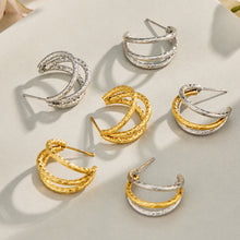 Gold and steel double layer hoop earrings arranged together on a neutral jewelry display