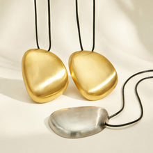 Gold-plated and polished steel pebble pendant necklace finish options displayed together