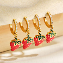 Row of gold strawberry charm huggie earrings showing the colorful fruit design