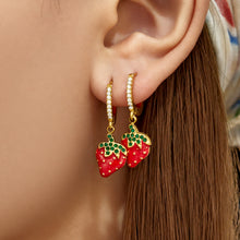 Model wearing gold PVD strawberry charm huggie earrings with sparkling zirconia hoops