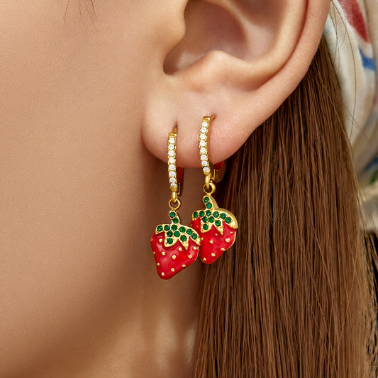 Model wearing gold PVD strawberry charm huggie earrings with sparkling zirconia hoops